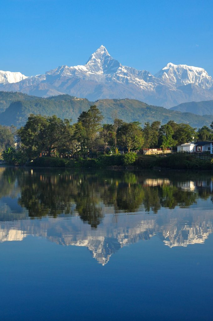 Stunning view of Machapuchare and Annapurna reflecting in a serene lake in Pokhara, Nepal.